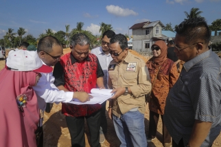 Saproni, Asep Nurdin dan Suryani memperhatikan rencana pembangunan Pelabuhan Tanjunguban